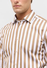 Gestreepte shirt in bruin en wit, met een knoopsluiting aan de voorkant, een puntige kraag en gemaakt van lichtgewicht stof met een gladde textuur.