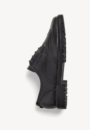 Chaussure noire en cuir avec un design brogue, des côtés texturés et une semelle en caoutchouc épaisse. Présente des lacets visibles et des perforations décoratives.