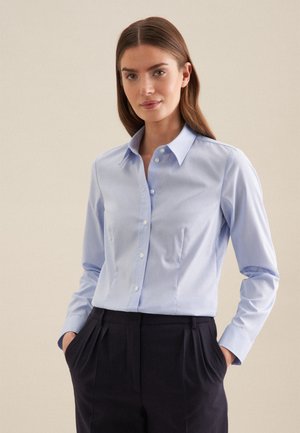 Lichtblauw button-up shirt met lange mouwen, gemaakt van soepel materiaal. Heeft een klassieke kraag en subtiele plooien aan de voorkant, gecombineerd met donkere broeken.