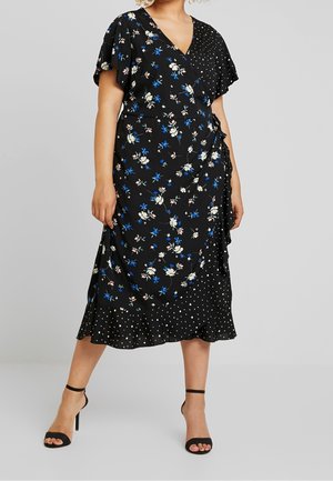 Černé midi zavinovací šaty s modrými a bílými květinovými a puntíkovanými vzory, s volánovými rukávy a volánkovým lemem, nošené s černými sandály na vysokém podpatku.