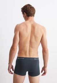 Tajtande mörkgrå boxerkalsonger med en bred midjeband som har varumärket "Marc O'Polo" i vit text.