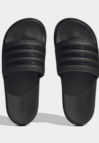 Sorte strandsandaler med en tekstureret gummisål, tre vandrette striber på remmen og præget logo på sålen.