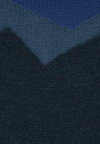 Tessuto lavorato a maglia con motivo a chevron, caratterizzato da strisce zigzag di blu scuro, blu medio e blu chiaro.