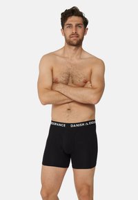 Svarta boxershorts med ett vitt elastiskt midjeband märkt "DANISH ENDURANCE." Har en framficka och en åtsittande design. Mjuk tygtextur.