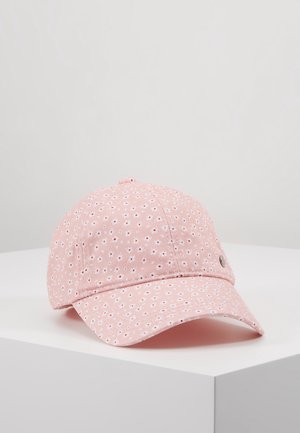 Lyserød kasket med små hvide og røde blomsterprint, der hviler på en hvid overflade mod en ensfarvet baggrund.