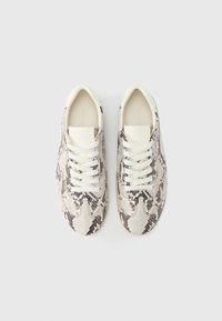 Αθλητικά παπούτσια με υφή φιδίσιου μοτίβου σε λευκό, γκρι και μαύρο. Διαθέτουν λευκά κορδόνια και λείο καουτσούκ σόλα. Άποψη από πάνω.