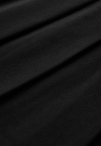 Tissu noir à texture lisse, présentant des plis subtils et un motif uniforme, mettant en avant un design minimaliste.