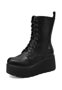 Botas de plataforma negras hechas de cuero suave, con un frente con cordones, punta redonda y suela gruesa de goma. Presenta un logotipo en el costado.