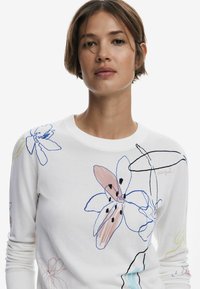 Maglione bianco con ricami floreali colorati in blu, rosa e nero. Girocollo con polsini a costine e vestibilità comoda.