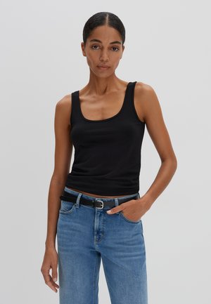 Zwarte katoenen tanktop met brede schouderbanden, ronde halslijn en een aansluitende pasvorm, gecombineerd met een blauwe jeans en een zwarte riem.