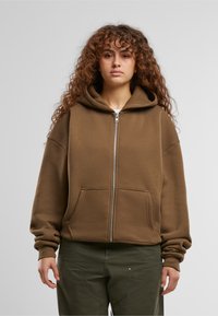 Brauner Reißverschluss-Hoodie aus weichem, strukturiertem Stoff mit einer großen Kapuze, zwei Vordertaschen und gerippten Bündchen und Saum.