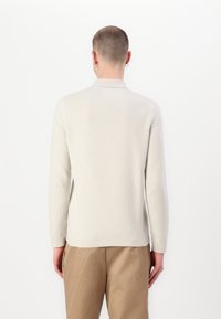 Kerge beež pika varrukaga polo särk, mis on valmistatud pehmest materjalist, kaelusega, minimalistliku disaini ja sileda tekstuuriga.