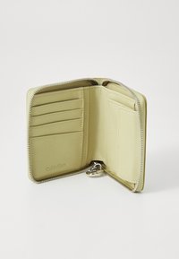 Portefeuille zippé en cuir vert avec plusieurs emplacements pour cartes et un petit compartiment à pièces. Présente une texture lisse et des détails en matériel argenté.