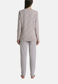 Completo di abbigliamento da casa in due pezzi. La parte superiore presenta un motivo a quadri rosa su un tessuto leggero; i pantaloni sono di un grigio chiaro uniforme, con una vestibilità comoda e polsini alla caviglia.