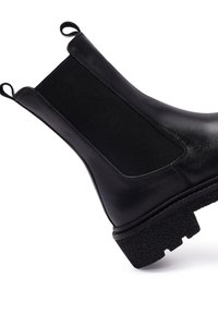 Czarne skórzane botki za kostkę z elastycznymi panelami bocznymi, teksturowaną czarną gumową podeszwą oraz tylną pętelką ułatwiającą zakładanie.