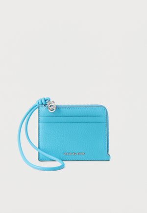 Heldere blauwe leren kaarthouder met polsriem, zilveren Michael Kors-logo en klein zilveren ritsbedeltje.
