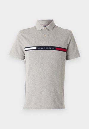 Gray polo shirt with collar, two buttons, and horizontal Tommy Hilfiger branding in navy, white, and red across the chest. Soft texture.