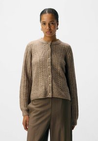 Bruine gebreide cardigan met een textuur kabelpatroon, ronde halslijn en een voorknoopsluiting met crèmekleurige knopen; ribbelmanchetten en -zoom.