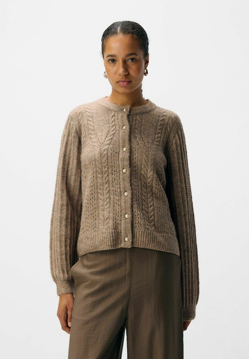 Bruine gebreide cardigan met een textuur kabelpatroon, ronde halslijn en een voorknoopsluiting met crèmekleurige knopen; ribbelmanchetten en -zoom.