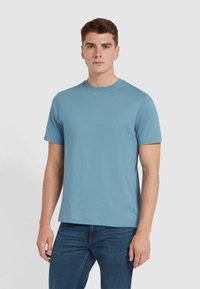 T-shirt in cotone azzurro chiaro con collo rotondo classico, maniche corte e un piccolo logo ricamato sul lato sinistro del petto.