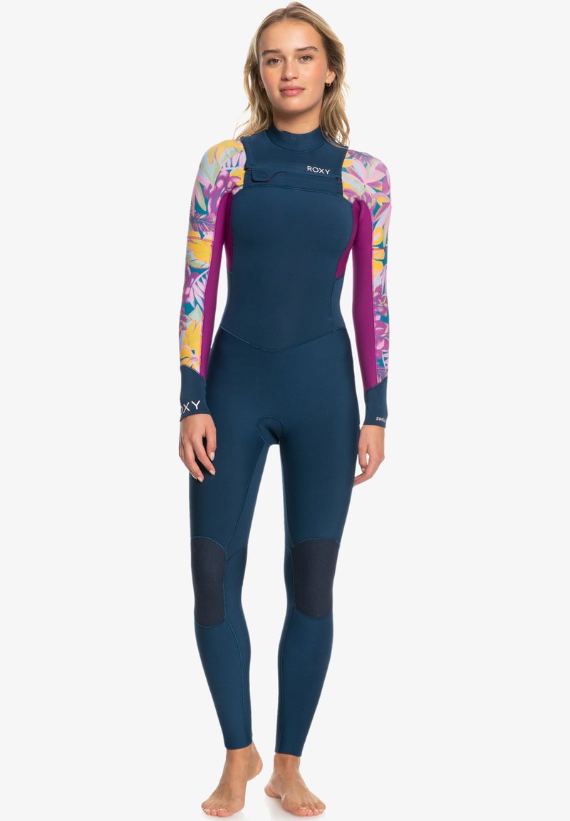 Traje de neopreno de manga larga en azul oscuro con mangas de estampado floral en rosa y púrpura. Cuenta con parches en las rodillas y un diseño de cremallera frontal.