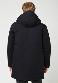 Parka isolante nera con un ampio cappuccio, caratterizzata da un taglio dritto, polsini elasticizzati e una texture liscia. Nessuna ferramenta o motivo visibile.