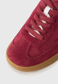 Maronn suede sneakers med teksturert overflate, avrundet tå og tykk gummisåle. Har matchende snøringer og sømdetaljer.