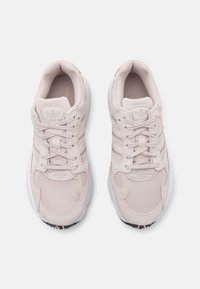 Hellrosa Sportschuhe aus Mesh- und Wildledermaterialien, mit drei seitlichen Streifen, Schnürverschluss und weißen Gummisohlen.