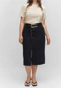 Černá džínová sukně s předním rozparkem, opásaná stříbrnou přezkou. Nošena s krémovým tričkem a černými žabkami. Jednoduchý design.