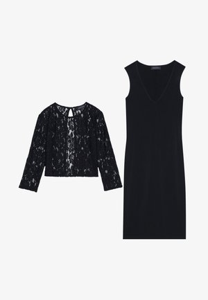 Top scurt din dantelă neagră cu mâneci lungi și detaliu de decupaj în spate, alăturat unei rochii negre ajustate cu decolteu adânc în V și fără mâneci.