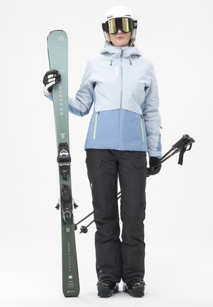 L'équipement de ski comprend une veste bleu clair et grise avec des accents néon, un pantalon noir, un ski vert avec des fixations noires et des bâtons de ski.