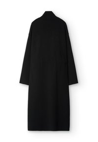 Pitkä musta takki, jossa korkeahko kaulus ja ylisuurennetut hihat. Valmistettu teksturoidusta kankaasta, jossa suora leikkaus eikä näkyviä kiinnityksiä.