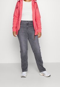 Grijze denim jeans met een rechte pasvorm, hoge taille en subtiele vervaging. Gepaard met een wit T-shirt en een roze hoodie met rits.