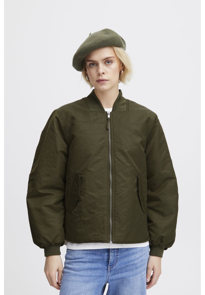 Veste bomber vert olive avec une fermeture éclair sur le devant, des poignets côtelés et deux poches latérales. Matériau doux et texturé ; coupe oversize.