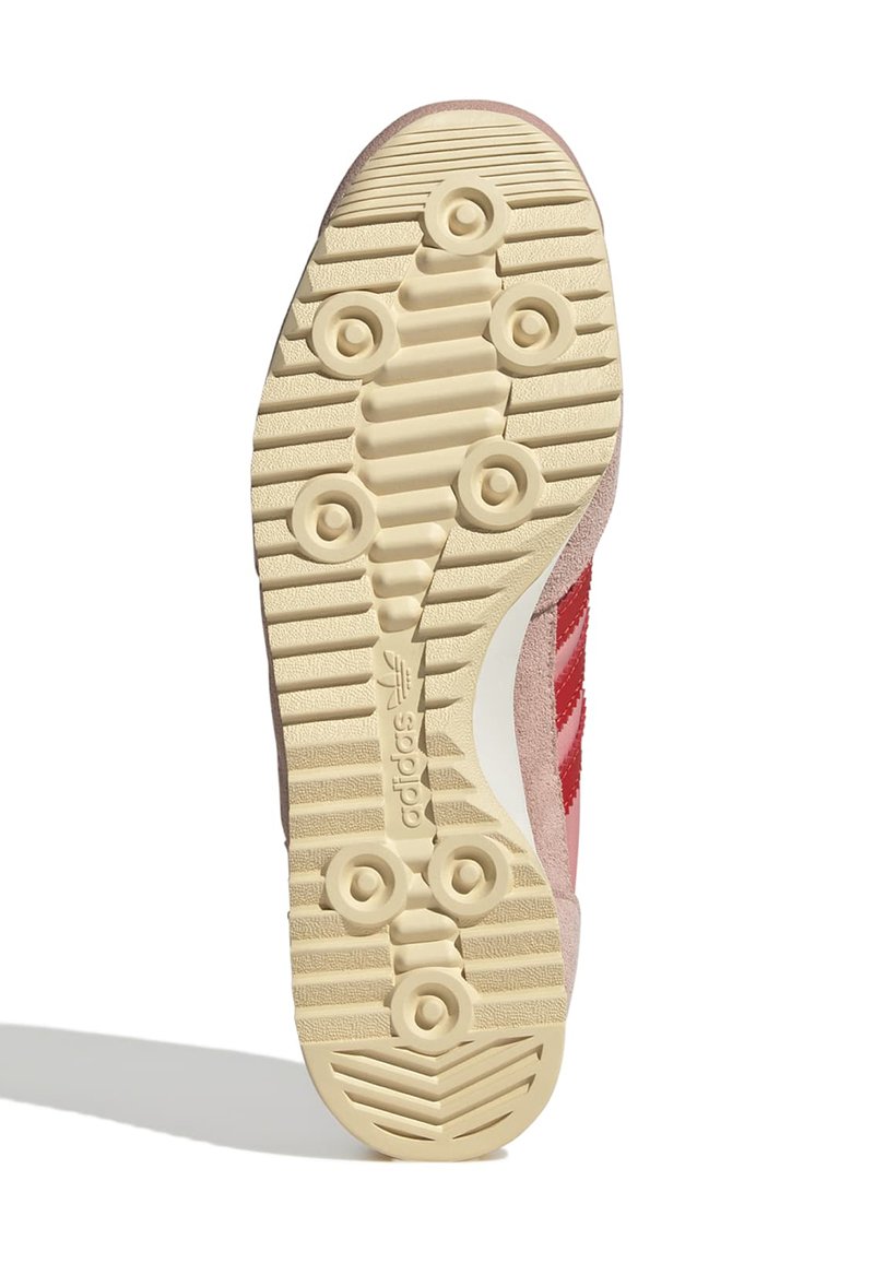 Semelle de sneaker en suède rose avec caoutchouc beige texturé, dotée de grips circulaires et d'un logo adidas, conçue pour l'adhérence et le confort.