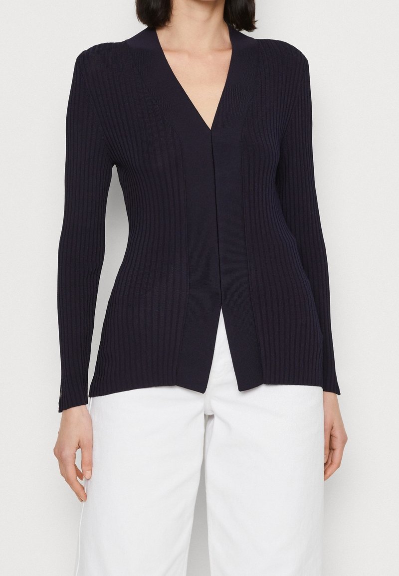 Marineblauwe ribgebreide cardigan met een V-hals, lange mouwen en een rechte snit, met een gladde textuur en zonder zichtbare sluitingen.