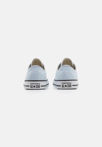 Svijetloplavi platneni tenisice s bijelim gumenim potplatima i crnim prugama, sa 'Converse All Star' oznakom na peti.