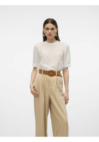 Top blanco de manga corta con un patrón zigzag texturizado, combinado con pantalones beige de tiro alto y un cinturón marrón circular.
