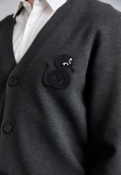 Cardigan grigio carbone con scollatura a V, caratterizzato da una applique di serpente nera con dettagli bianchi sul lato sinistro e cinque bottoni neri.