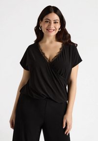 Czarna bluzka z krótkim rękawem, z dekoltem w kształcie litery V i koronkowymi detalami. Miękka tkanina o gładkiej fakturze, w połączeniu z czarnymi spodniami.