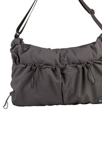 Gray nylon shoulder bag with cinched design, adjustable strap, front pockets, and toggle accents. Smooth texture, soft finish, minimal branding.