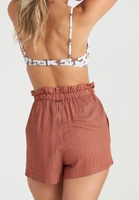 Shorts a righe marroni a vita alta con fascia elastica arricciata in vita, abbinati a un reggiseno a fiori bianco e marrone.