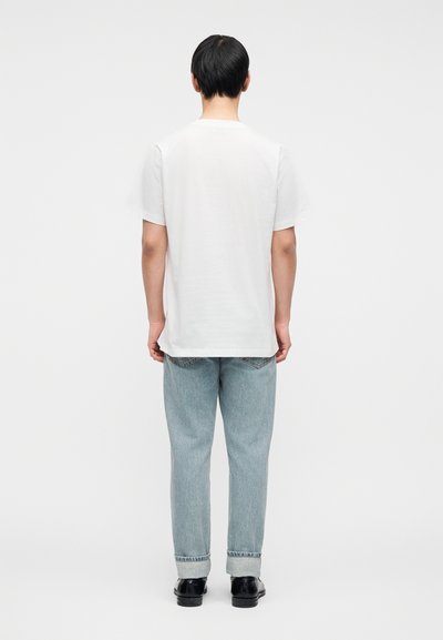 Λευκό βαμβακερό μπλουζάκι με άνετη εφαρμογή, σε συνδυασμό με ανοιχτό μπλε τζιν παντελόνι με ευθεία γραμμή και γυρισμένα μανίκια.