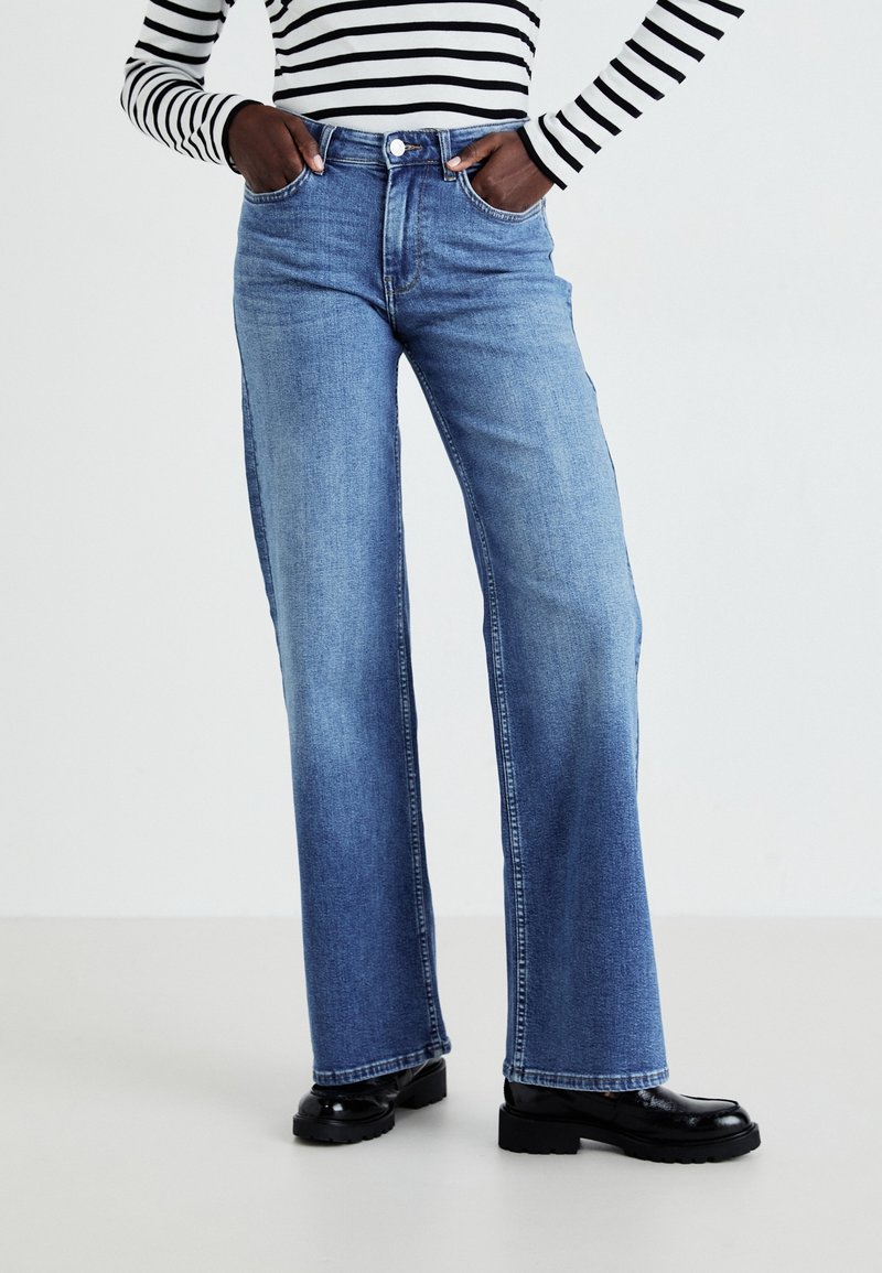 High-waisted, wide-leg blue jeans made from denim, featuring front pockets, a button closure, and a faded finish on the legs.