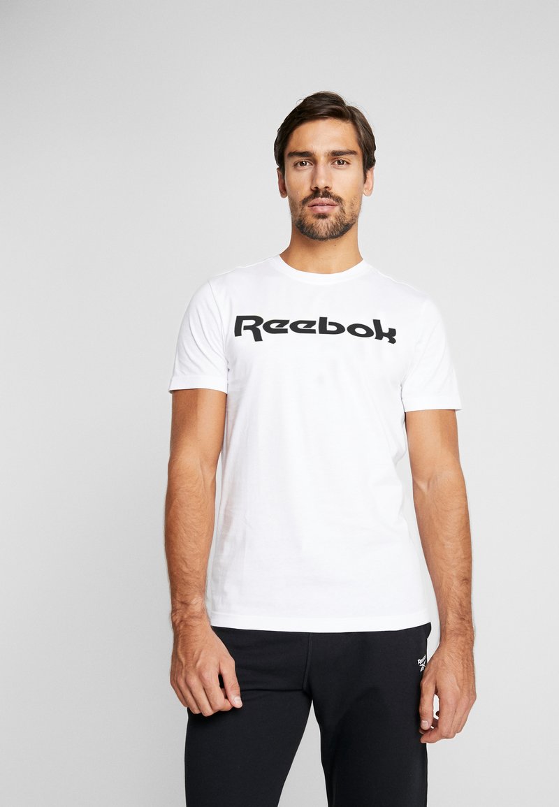 Hvitt bomull T-skjorte med et stort svart Reebok-logo over brystet. Korte ermer og rund hals.