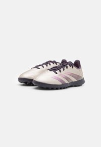 Chaussures de football légères avec une tige argentée, des accents violets et des détails texturés ; elles comportent une semelle en caoutchouc sombre et un système de laçage.