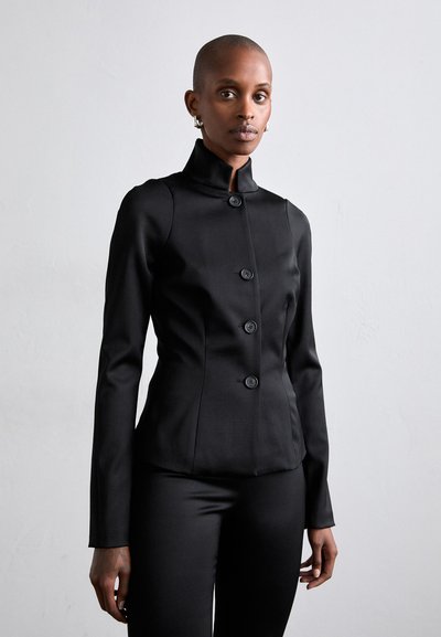Blazer nero aderente con colletto alto e cinque grandi bottoni. Realizzato in tessuto liscio, presenta maniche lunghe e una silhouette sartoriale.