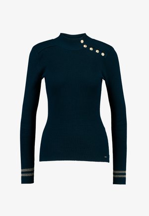 Tummanpetroolinvärinen, ribbineulottu korkeakauluksinen neule, jossa kullansävyiset koristeelliset napit olkapäällä ja raidalliset yksityiskohdat hihansuissa.