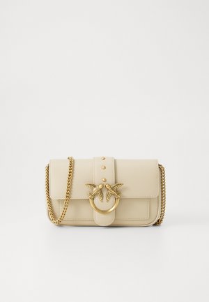 Borsa in pelle beige con una tracolla in catena dorata, caratterizzata da una chiusura decorativa con due uccelli e un anello metallico circolare, e una chiusura a soffietto.
