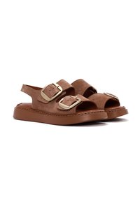 Sandalias de ante marrón con dos correas anchas, grandes hebillas doradas, punta abierta y una suela gruesa y duradera. Presentan un diseño tipo slingback.
